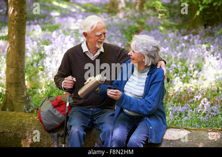 Älteres paar ruht auf Spaziergang durch Bluebell Holz Stockfoto