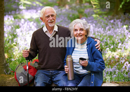 Älteres paar ruht auf Spaziergang durch Bluebell Holz Stockfoto