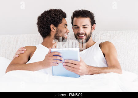 Glückliches schwules Paar mit tablet Stockfoto