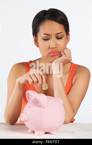 Unglückliche, Münze ins Sparschwein Stockfoto