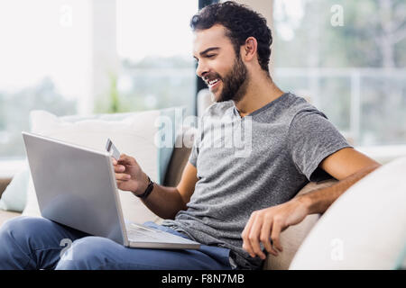 Glücklicher Mann mit Laptop und Kreditkarte Stockfoto