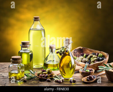 Glasflaschen von Olivenöl und einige Beeren auf dem Holztisch. Studio gedreht. Stockfoto