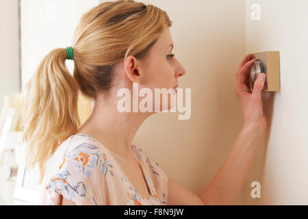 Frau, die Zentralheizung Thermostatsteuerung einstellen Stockfoto