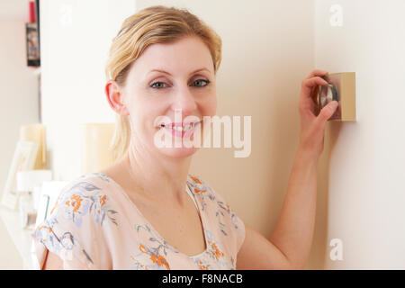 Frau, die Zentralheizung Thermostatsteuerung einstellen Stockfoto