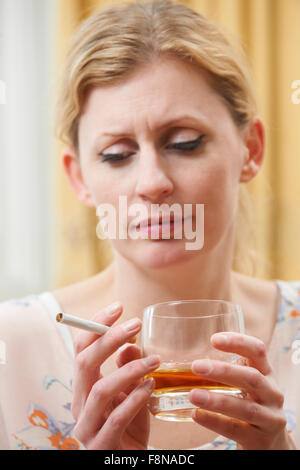 Frau mit Glas Whisky und Zigaretten Stockfoto