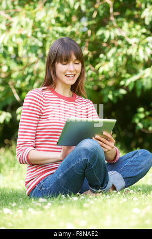 Attraktive junge Frau mit Digital-Tablette im Park Stockfoto