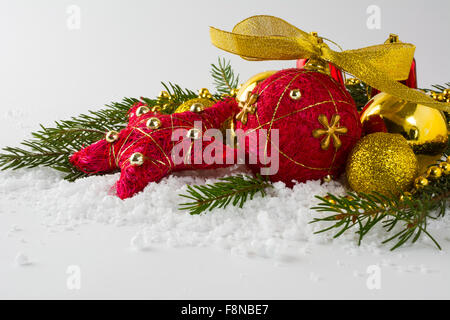 Roten Stroh Christbaumschmuck und goldene Kugeln, verzweigt sich Tannen im Schnee auf einem weißen Hintergrund Stockfoto