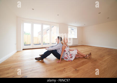 Junges Paar sitzt im leeren Raum des Traumhauses Stockfoto