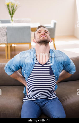 Gut aussehender Mann mit Rückenschmerzen auf sofa Stockfoto