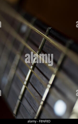 Schwingenden Saiten einer Gitarre mit engen Fokus auf einen Bund auf dem Gitarrenhals Stockfoto