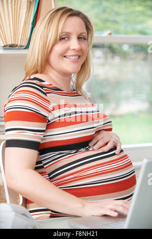 Glücklich schwanger Frau sitzen am Schreibtisch im Home Office Stockfoto