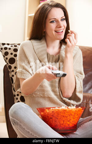 Junge Frau vor dem Fernseher beim Popcorn Essen genießen Stockfoto