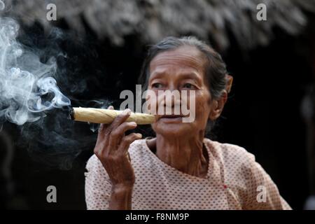 Lächelnde asiatische Frau raucht eine Zigarre Aufnahme in einem kleinen Dorf in der Nähe von Heide, in Myanmar Burma, wo eine Frau Zigarren b tut Stockfoto