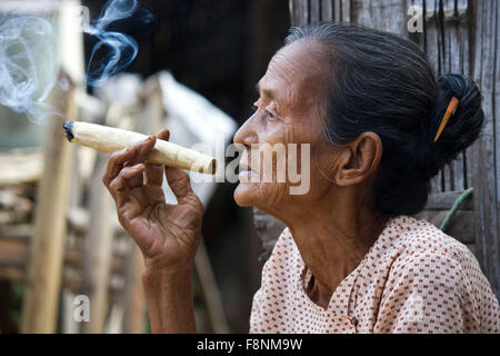 asiatische Frau raucht eine Zigarre Aufnahme in einem kleinen Dorf in der Nähe von Heide, in Myanmar Burma, wo eine Frau Zigarren durch innovative tut Stockfoto