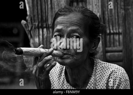 Frau raucht eine Zigarre Aufnahme in einem kleinen Dorf in der Nähe von Heide, in Myanmar Burma, wo eine Frau von sich selbst und Sm Zigarren tut Stockfoto