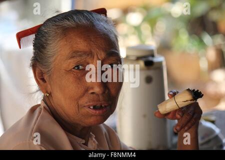 Alte asiatische Frau einer handgemachten Zigarre mit einem Kamm auf dem Haar Stockfoto