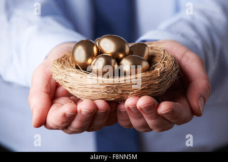 Geschäftsmann Holding Nest voller goldenen Eiern Stockfoto