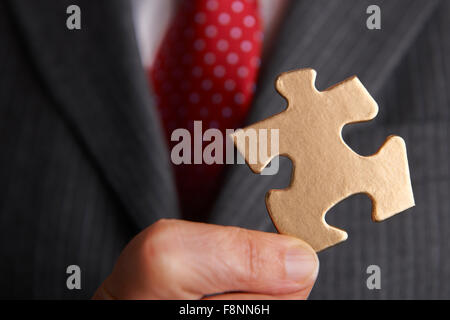 Geschäftsmann mit goldenen Puzzleteil Stockfoto