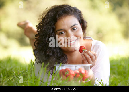 Hübsche junge Frau Essen Erdbeeren im freien Stockfoto