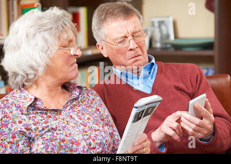 Älteres Paar versucht, Handy betreiben verwechselt Stockfoto