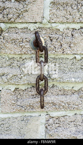 Kurzes Stück verrosteten braun Kette Übergabe von Schraube in der Wand verankert. Stockfoto