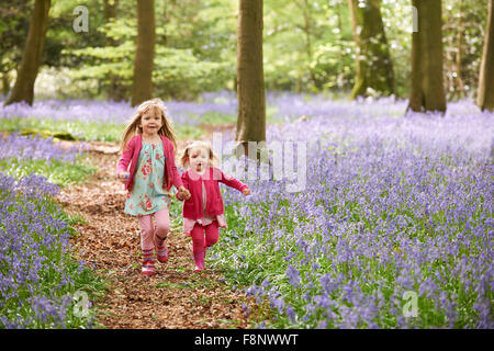 Zwei Mädchen zusammen laufen durch Bluebell Woods Stockfoto