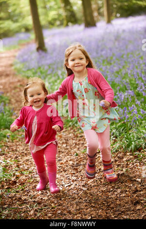 Zwei Mädchen zusammen laufen durch Bluebell Woods Stockfoto