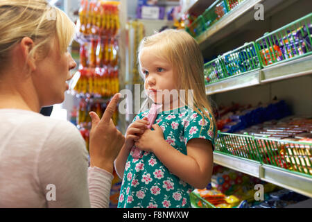 Kind mit Arguement mit Mutter an Süßigkeiten Theke Stockfoto