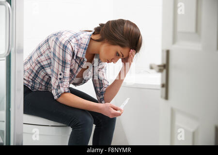 Teenager-Mädchen sitzen im Badezimmer mit Schwangerschaftstest Stockfoto