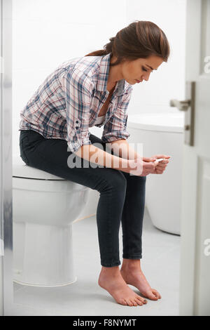 Teenager-Mädchen sitzen im Badezimmer mit Schwangerschaftstest Stockfoto