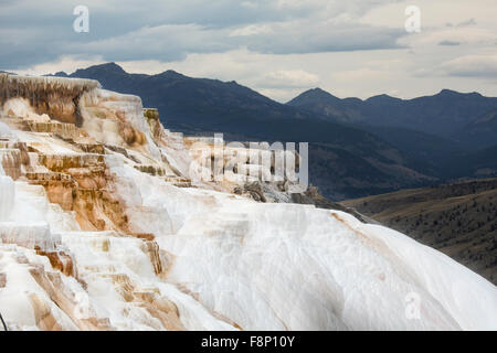 Erdwärme Strom von heißen, Carbonat reichen Wasser, Formulare, cascading, dunkel orange Travertin Terrassen, mit Bergen im Hintergrund Stockfoto