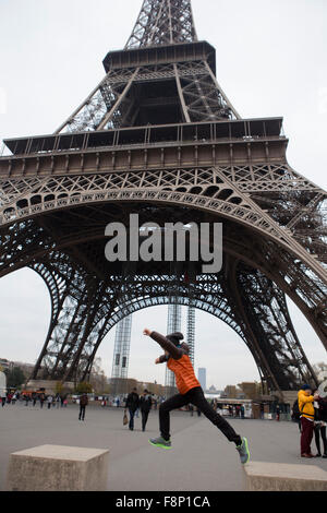 Ein kleiner Junge springt von einem konkreten Stuhl zur anderen am Fuße des Eiffelturms in Paris, Frankreich. Stockfoto