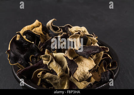 Schwarzen Keramikschale mit getrockneten Pilzen in Auricularia Polytricha, Wolke Ohr Pilz oder Chinesisch schwarze Pilz aufgetürmt. Nahaufnahme Stockfoto