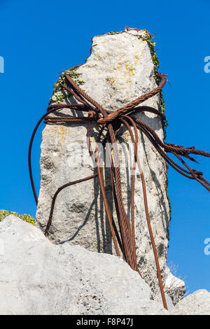 Alten rostigen Eisen Kabel geloopt um einen Kalksteinfelsen in einem Steinbruch. Stockfoto