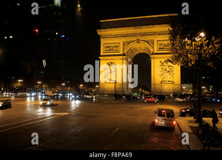 Autos fahren rund um die Basis des Arc de Triomphe nachts in Paris, Frankreich Stockfoto