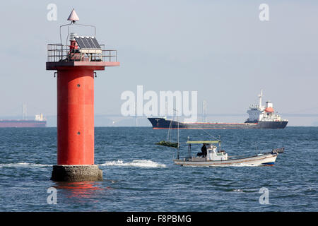 Leuchtturm mit Frachtschiff im Meer Stockfoto