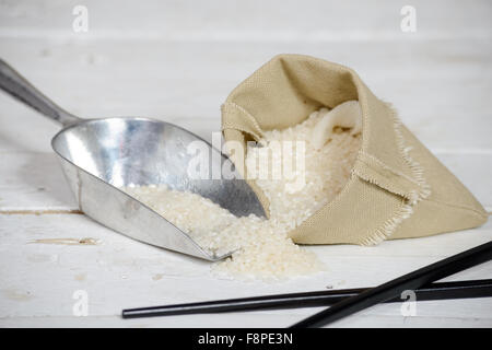 ein Reis in kleinen hessischen Tasche auf Holztisch Stockfoto