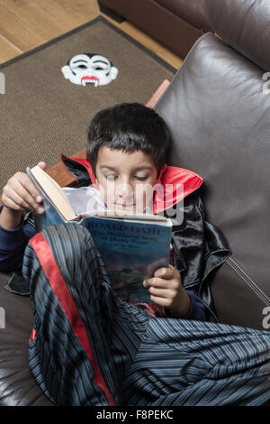 Junge, 8 im Halloween-Outfit, ein Buch zu lesen Stockfoto