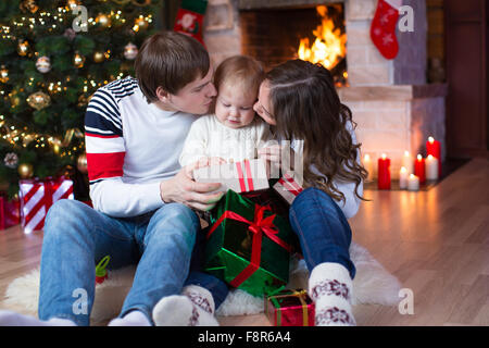 Glückliche Eltern küssen Söhnlein und Geschenke an Weihnachten und Silvester Stockfoto
