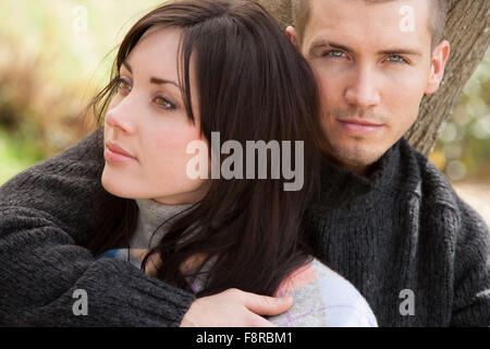 Attraktives junges Paar Türen kuscheln. Der Mann schaut die Kamera während seiner Partnerin zur Seite Weg sucht. Stockfoto