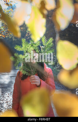 Frau mit Tanne Zweig vor Gesicht Stockfoto