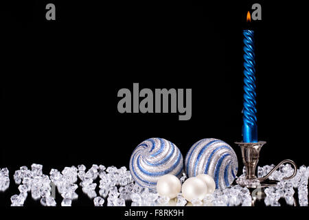 Silber Leuchter mit einem blauen Kerze und Glas Kugeln steht neben einer Vielzahl von Kristallsteine auf den Spiegel Stockfoto