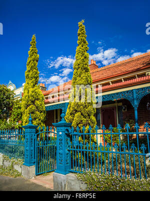 Periode eingeschossige rote Backsteinhaus mit blau lackierten Schmiedearbeiten Zaun und Laubsägearbeiten Albert Park, Melbourne Australien Stockfoto