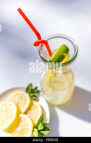 Limonade in der Kanne mit Strohhalmen und Zitronen auf weißem Hintergrund. Ansicht von oben Stockfoto