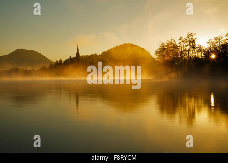 Sunrise bricht durch den Nebel über Lake Bled, Slowenien Stockfoto