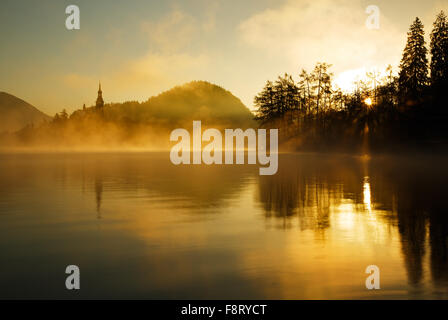Sunrise bricht durch den Nebel über Lake Bled, Slowenien Stockfoto