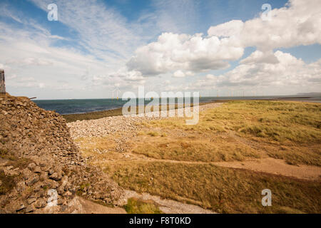 Ein Blick auf die Windenergieanlagen vor der Ostküste in Redcar Felsenküste und blau bewölktem Himmel zeigen Stockfoto