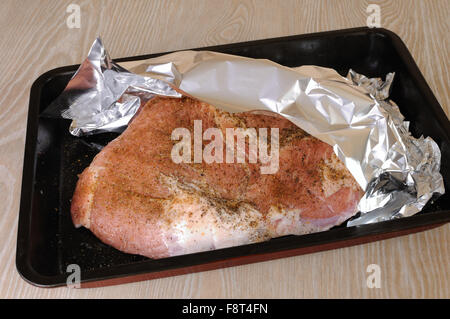 Ein Stück rohes Schweinefleisch Schinken auf ein Backblech unter der Folie Stockfoto