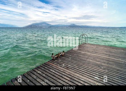 SIRMIONE, Italien - 4. April 2015: Touristen auf Pier mit bewölktem Himmel in Sirmione, Italien. Sirmione ist einer der beliebtesten Gardasee Stockfoto