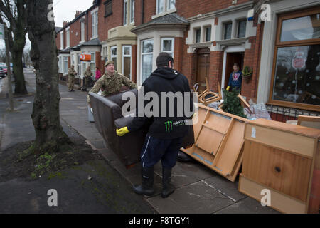 Ein Mitglied der Duke of Lancaster Regiment, mit Sitz in Preston, Lancashire, ein Bewohner von Warwick Road in Carlisle helfen entfernen Sie Möbel und andere Haushalte waren beschädigt durch Hochwasser am vergangenen Wochenende. Rekord Regen fallen in Cumbria verursacht Überschwemmungen auf mehrere Bereiche von Carlisle, wodurch Häuser durch Rettungsdienste evakuiert werden. Stockfoto